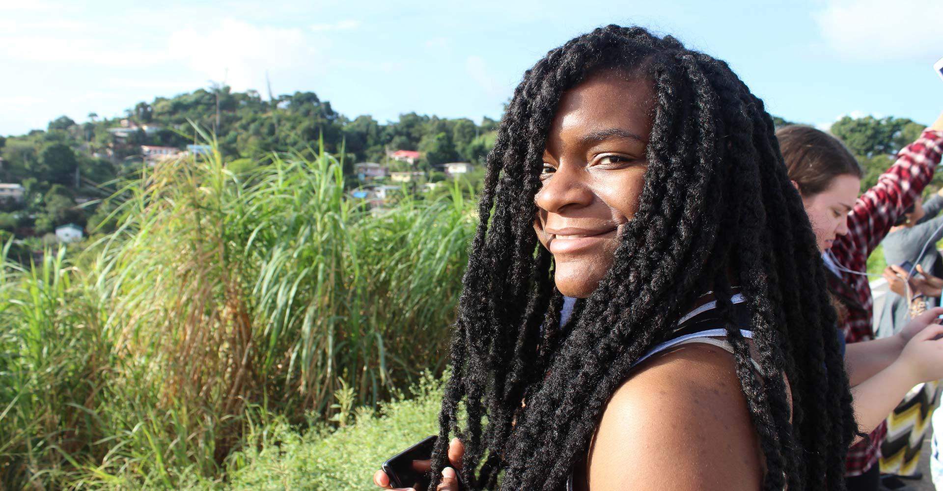 A student poses for a photo in front of hilly fields.